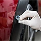 Gloved hand working on a red vehicle panel.